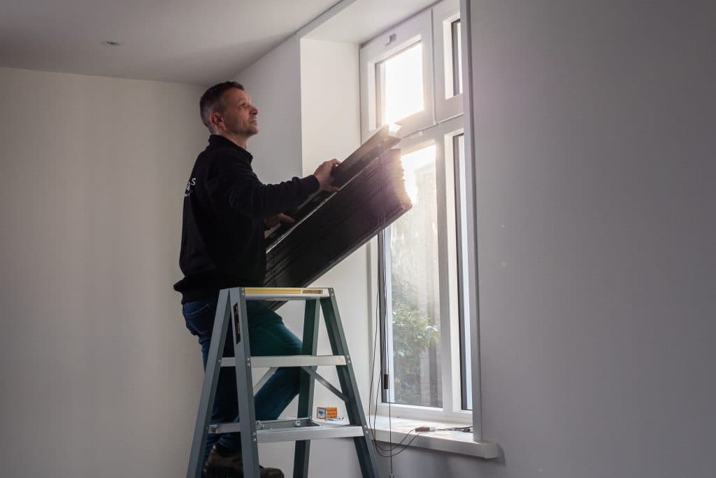 Twan hangt raamdecoratie op bij klanten